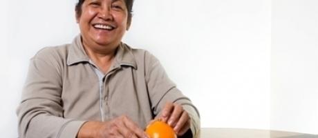 mature woman smiling and peeling an orange