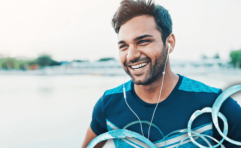 man smiling with headphones outdoors